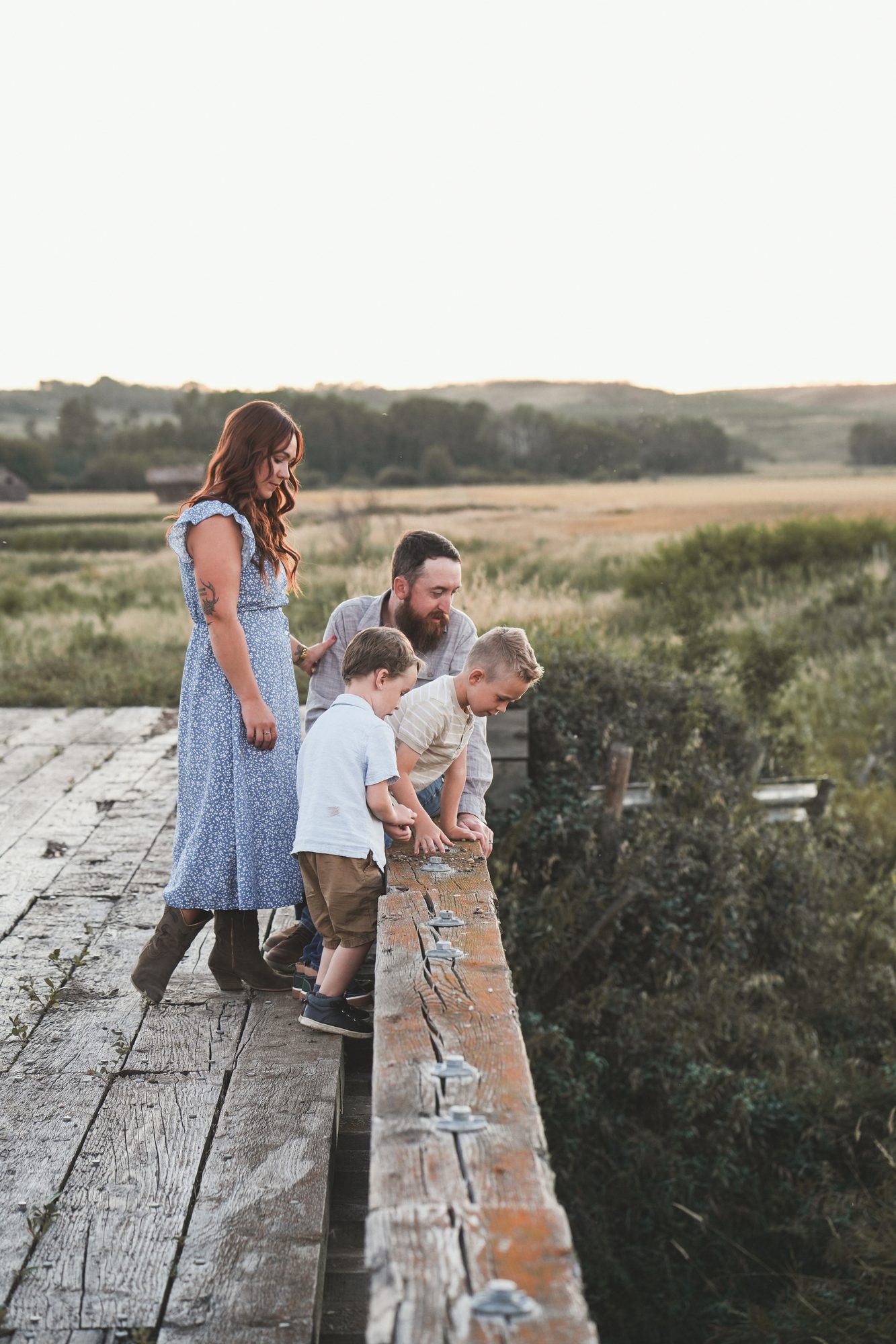 The family exploring together on an old wooden bridge at golden hour