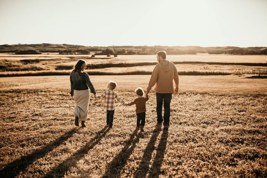 Rachael's family walking hand in hand through a golden field